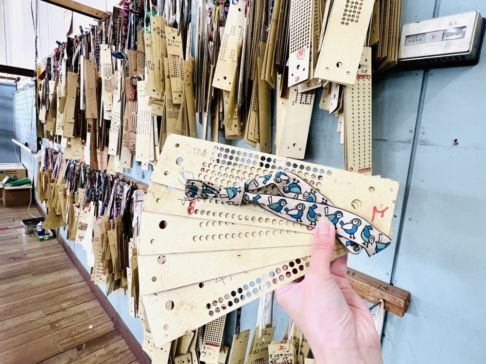 The machine reads the round holes (referring to the traditional punch-card system for looms) to create the intricate ribbon patterns.